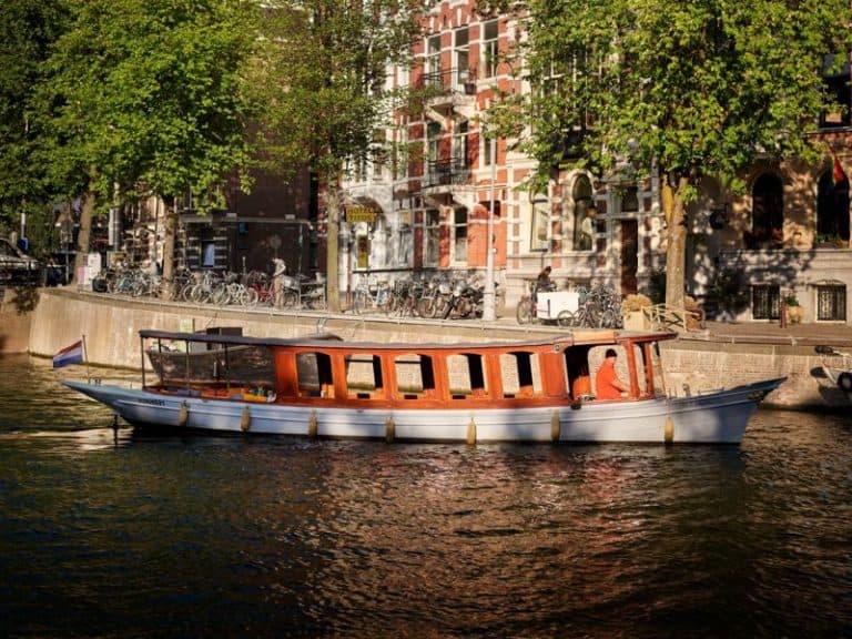 Salonboot Karssing met dak varen op Amsterdamse gracht
